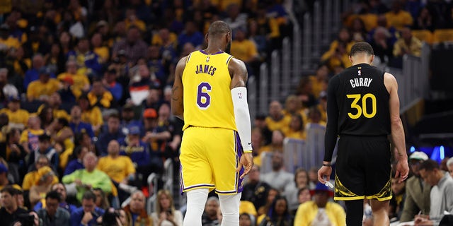 LeBron James stands next to Steph Curry on the basketball court