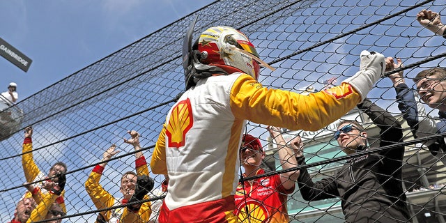 Josef Newgarden climbs the catch fence