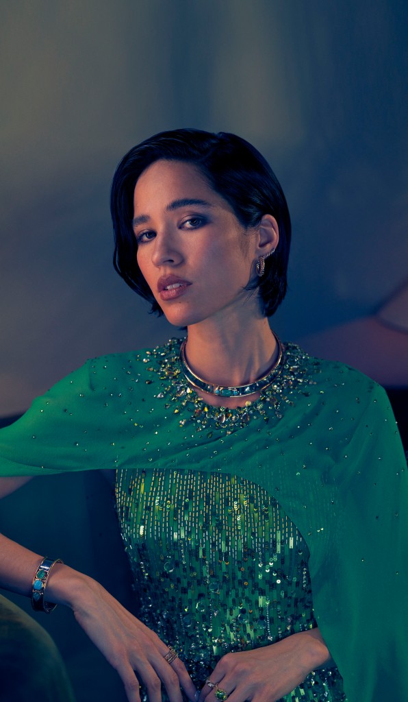 Jenny Packham dress, $6,395 at Farfetch.com; Hoop earrings (worn throughout), Asbille’s own; Marina B Trisolina earrings in 18-k yellow gold, $3,950, Simona collar necklace in 18-k yellow gold and titanium with turquoise and emeralds, $23,800, Simona bangle in 18-k yellow gold and titanium with turquoise and emeralds, $21,600, Trisola ring (Asbille’s right hand) in 18-k yellow gold with emeralds, $6,250, Triangolini ring (Asbille’s left index finger) in 18-k yellow gold with diamonds, $4,500; London Collection ring (Asbille’s left middle finger) in 18-k yellow gold with peridot and diamonds, $4,650.