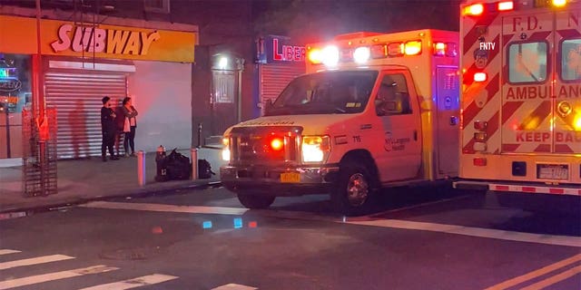 Ambulance driving down the street in front of a Subway.