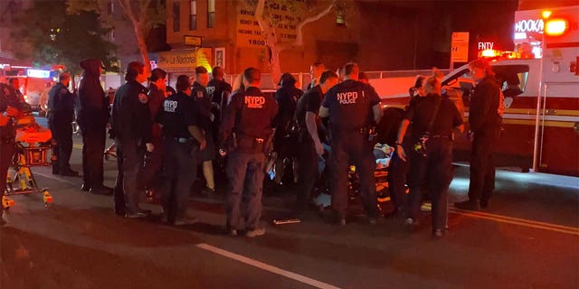 NYPD officers standing on the street next to an ambulance.