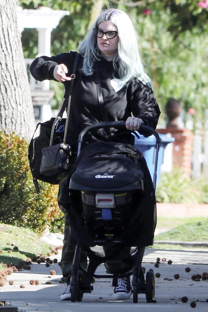Kelly Osbourne out for a stroll with baby Sidney. She pushes a stroller on a sidwalk. 