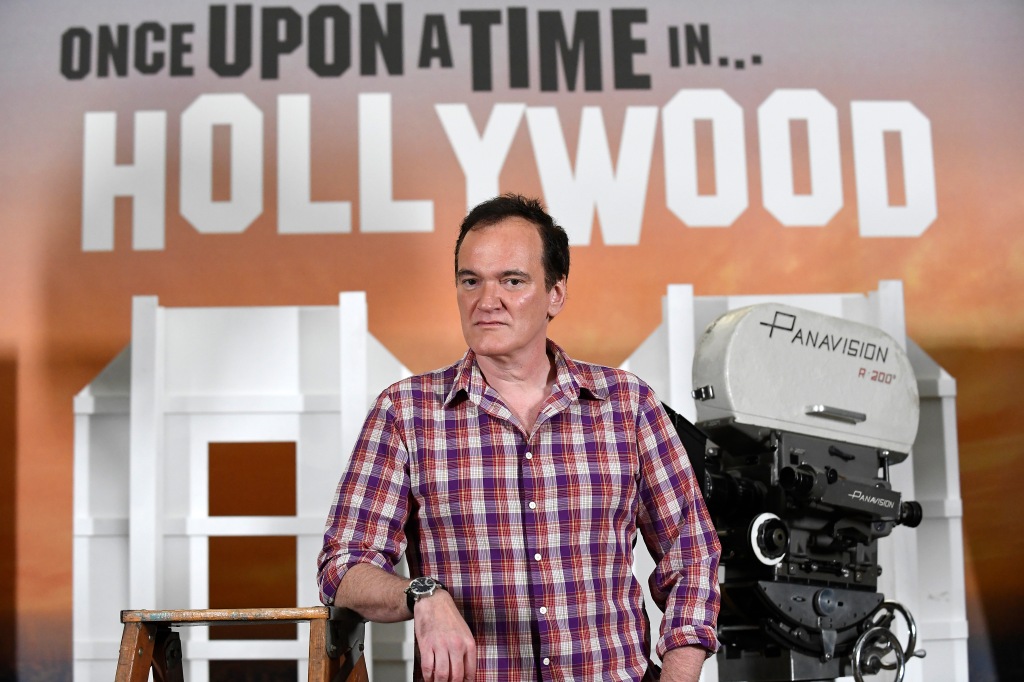 Quentin Tarantino standing in front of sign with movie title printed on it