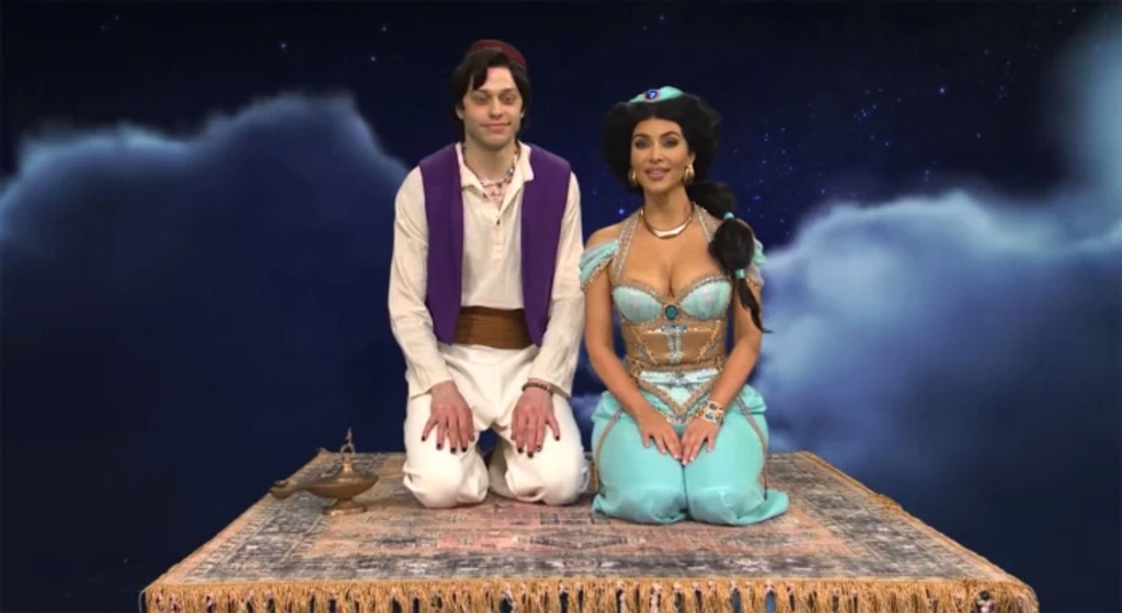 Pete Davidson and Kim Kardashian on "SNL" kneeling on a carpet. 