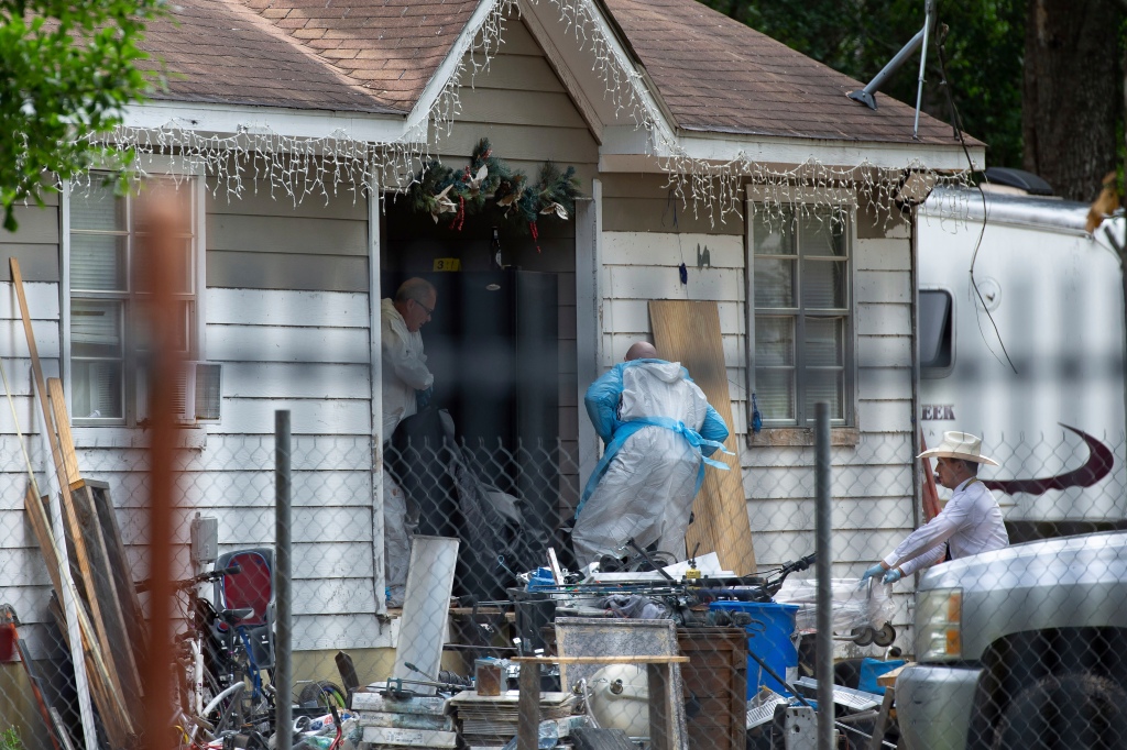 Law enforcement staff carry out five bodies from the home in Cleveland, Texas.