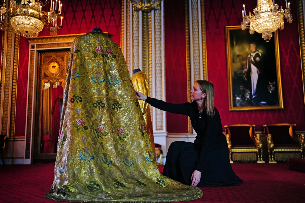 Woman adjusting giant gold cape in royal room.