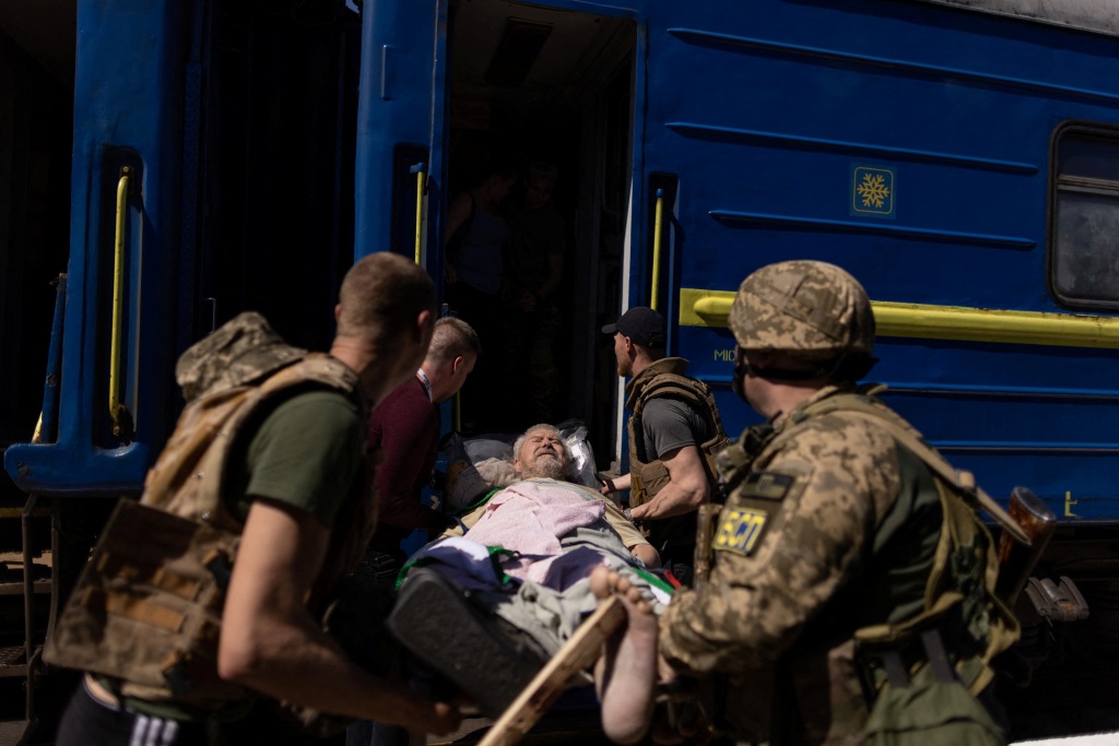 A wounded man is carried away at the site a train station hit by a Russian military strike, amid Russia's attack on Ukraine, in Kherson, Ukraine May 3, 2023. 