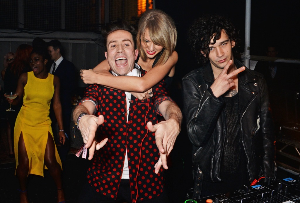 Nick Grimshaw, Taylor Swift and Matt Healy smiling, with Taylor hugging Nick. 