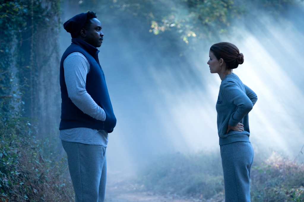 Brian Tyree Henry and Kate Mara stand outside facing each other wearing sweatpants. 