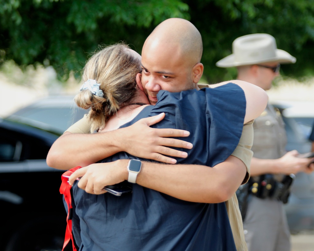Mall employees embrace as they greet each other the day after the shooting.