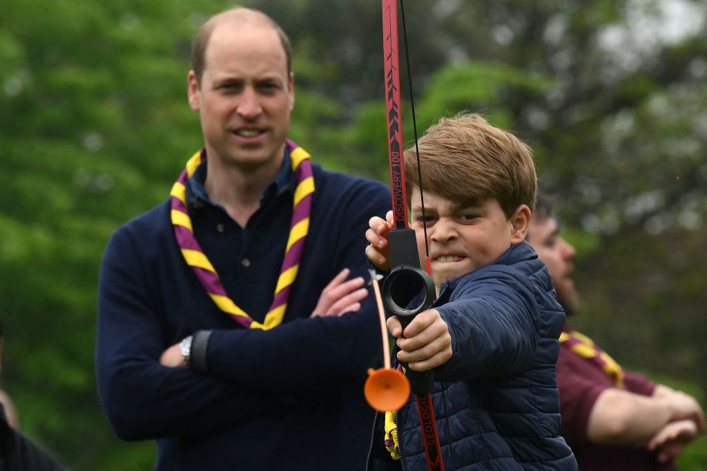 William looks on as George shoots an arrow.