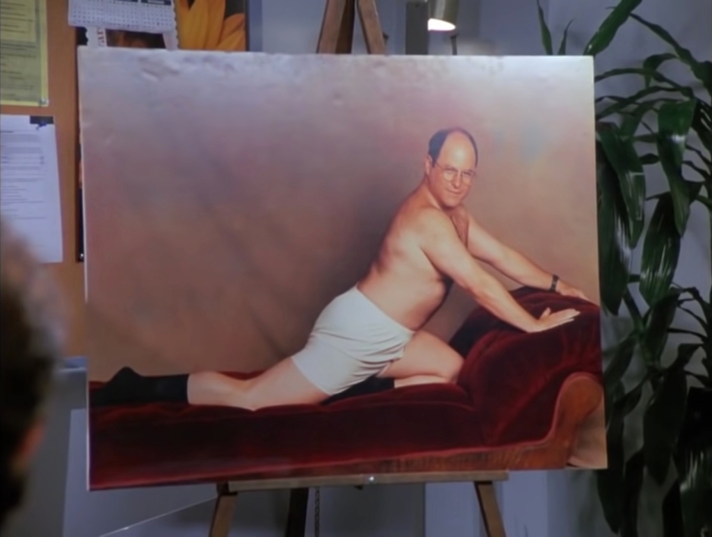 The picture on the stall comes from the fourth season of the series when George Costanza (played by Alexander) is convinced by Kramer (Michael Richards) to seduce "photo store Sheila” with the photos. 