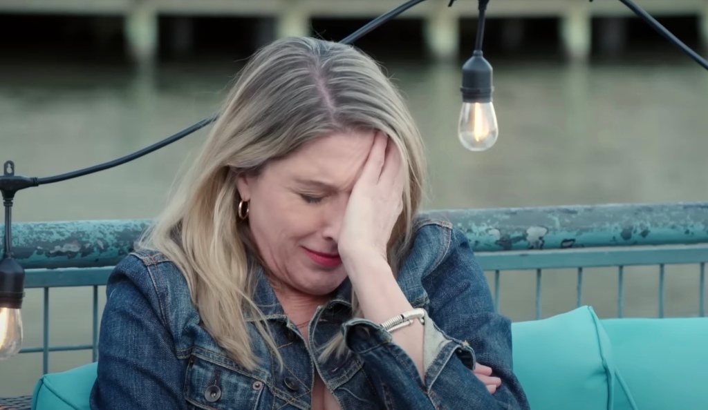 A blonde woman putting her face in her hands. 