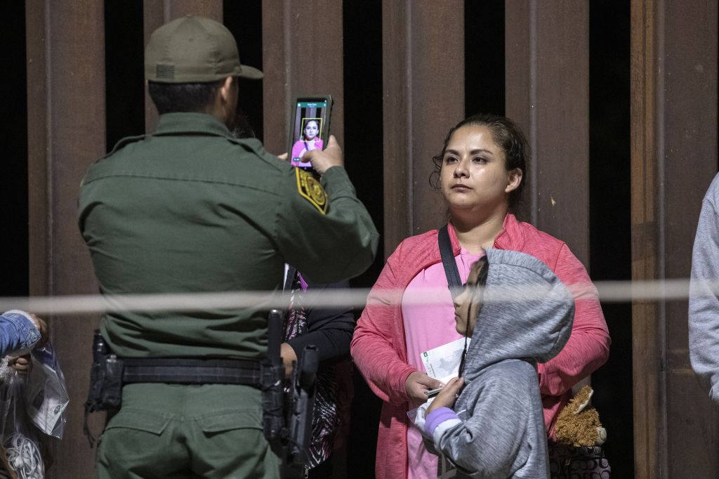 A migrant has her photo take by a Border Patrol agent.