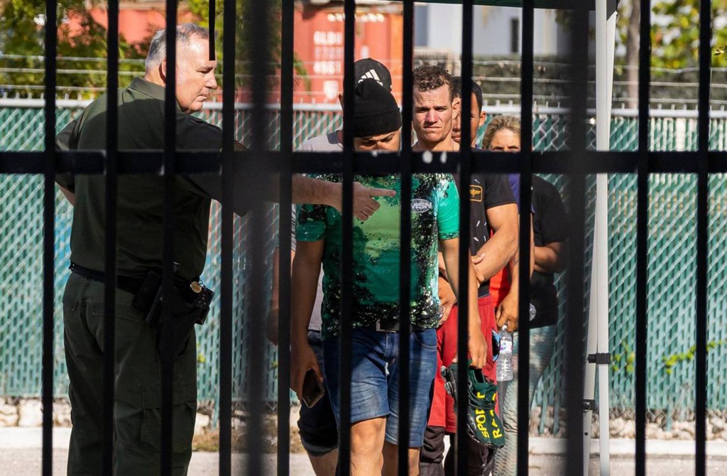 An officer directs a group of Cuban migrants at the U.S. Customs and Border Protection office on Sunday, Jan. 8, 2023, 