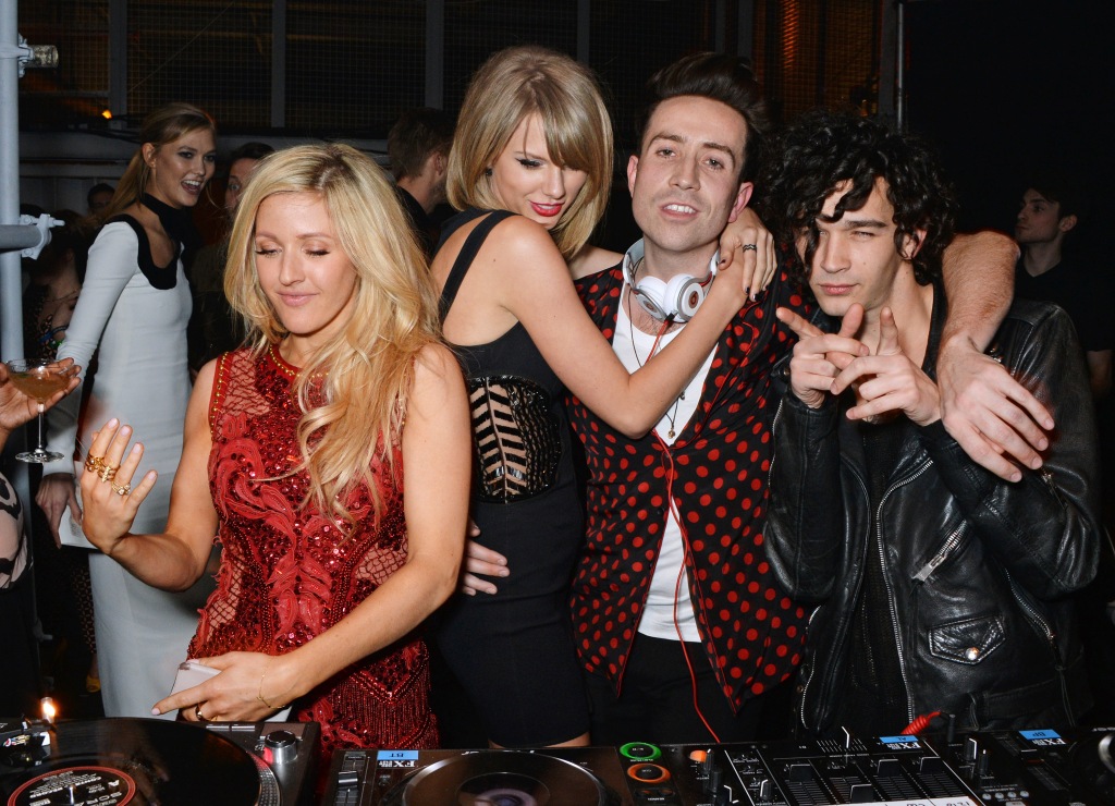 Karlie Kloss, Ellie Goulding, Taylor Swift, Nick Grimshaw and Matt Healy smiling standing together. 