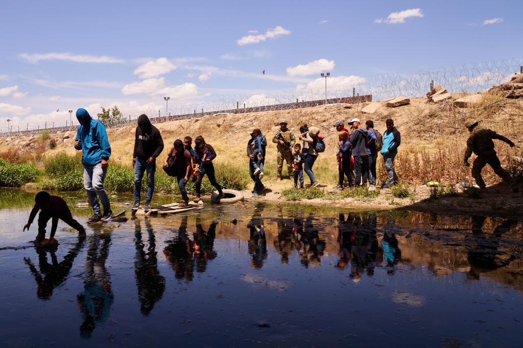 Migrants who crossed the U.S.-Mexico border  at the Rio Grande River are denied entry at the base of the Ysleta-Zaragoza bridge in El Paso, Texas as Texas National Guard soldiers install a second layer of concertina wire on Saturday, May 13, 2023.