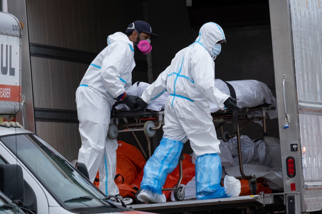 Workers move bodies to a refrigerated truck 