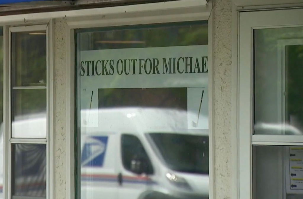 A sign in a window that says "Sticks out for Michael."