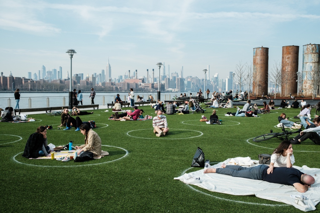 People enjoy warm weather in Domino Park which has circles painted on the grass to designate social distance. 