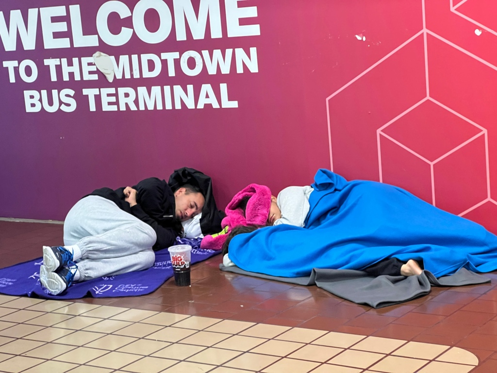 Migrants sleep at the midtown bus terminal in NYC