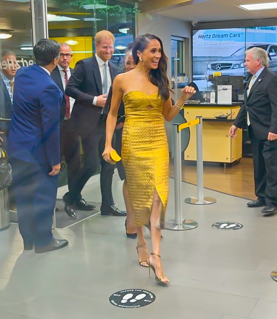 Markle was all smiles wearing a gold dress and matching heels.