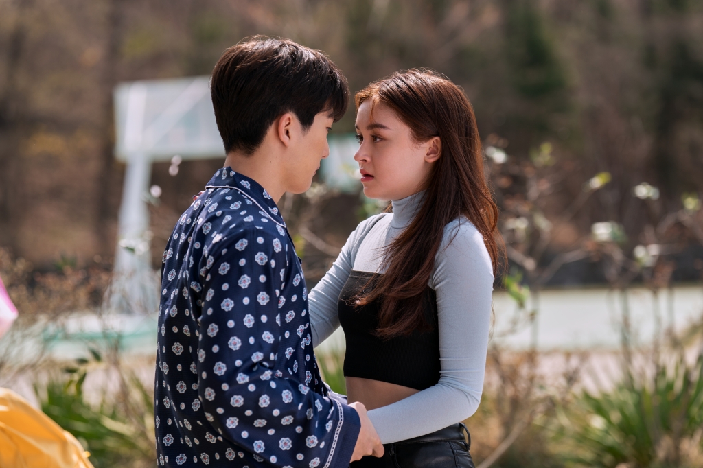 Choi Min-yeong as Dae and Anna Cathcart as Kitty Song Covey stand close outside. 