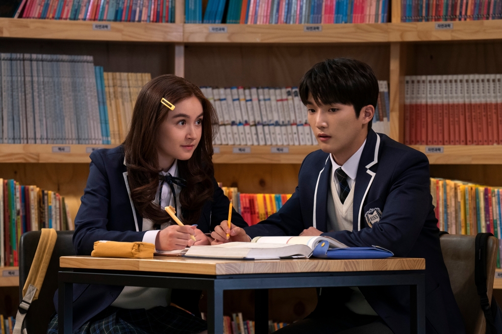 Anna Cathcart as Kitty Song Covey and Choi Min-yeong as Dae in "XO, Kitty." They're sitting at a table together in a school library. 