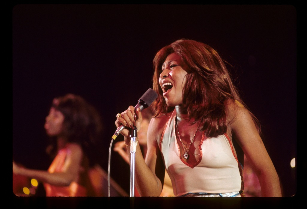 Tina Turner singing on stage in white shirt