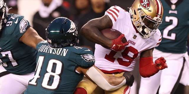 An Eagles player tackles a 49ers player