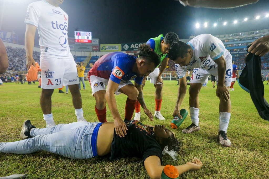 Soccer players attend a fan lying on the field of the Cuscatlan stadium in San Salvador, El Salvador, Saturday, May 20, 2023.