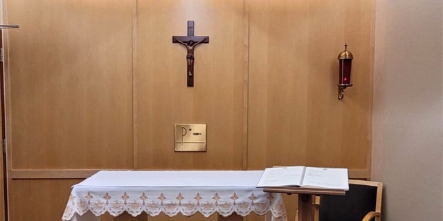 chapel with crucifix center, sanctuary candle at right