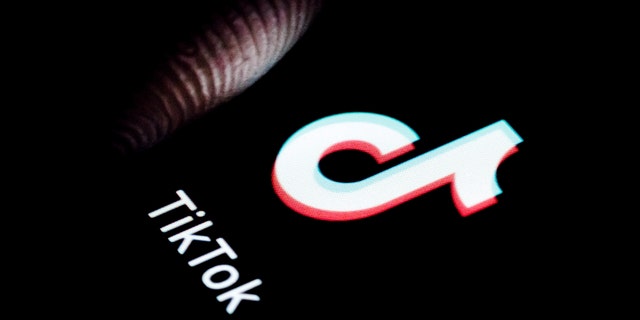 The logo of TikTok app on a phone and a finger