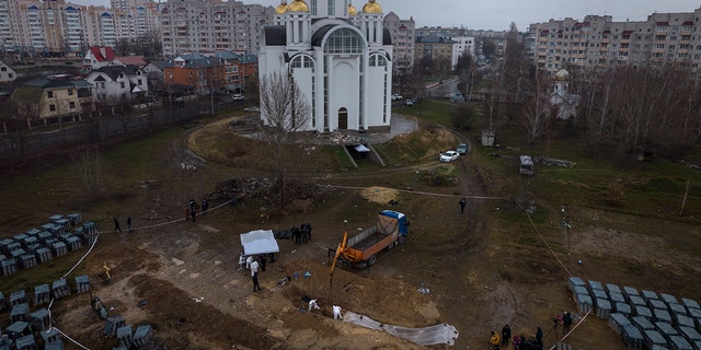 Cemetery workers work at a mass grave in Bucha, on the outskirts of Kyiv, Ukraine, to identify civilians killed during the war against Russia, Sunday, April 10, 2022.