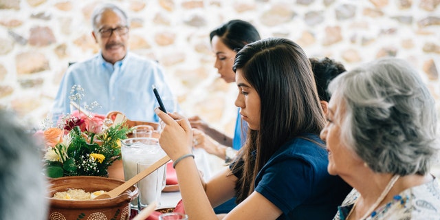 Teen on phone at dinner