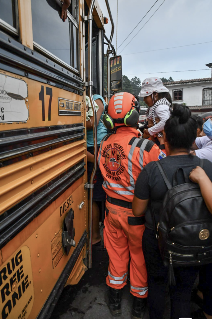 An official from The National Coordination for Disaster Reduction helps a young girl onto a bus during the evacuation orders. 