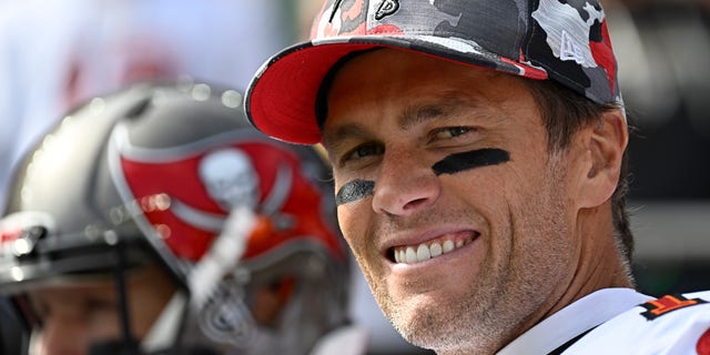 Tom Brady smiles in his camouflage Bucaneer's hat