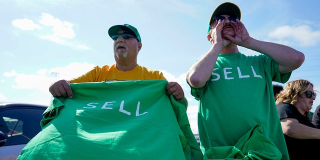 A's fans hold t-shirts that read "SELL"