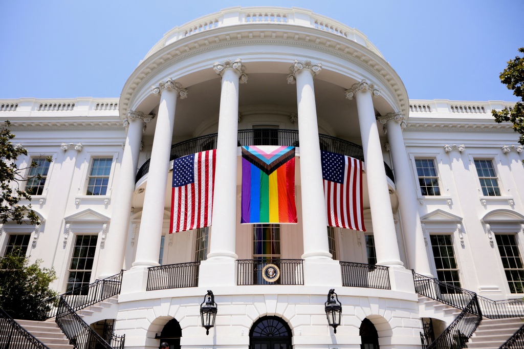 A Pride flag hangs in between to American flags from the balcony of the White House during a Pride Celebration in the South Lawn, hosted by President Joe Biden, on June 10, 2023.