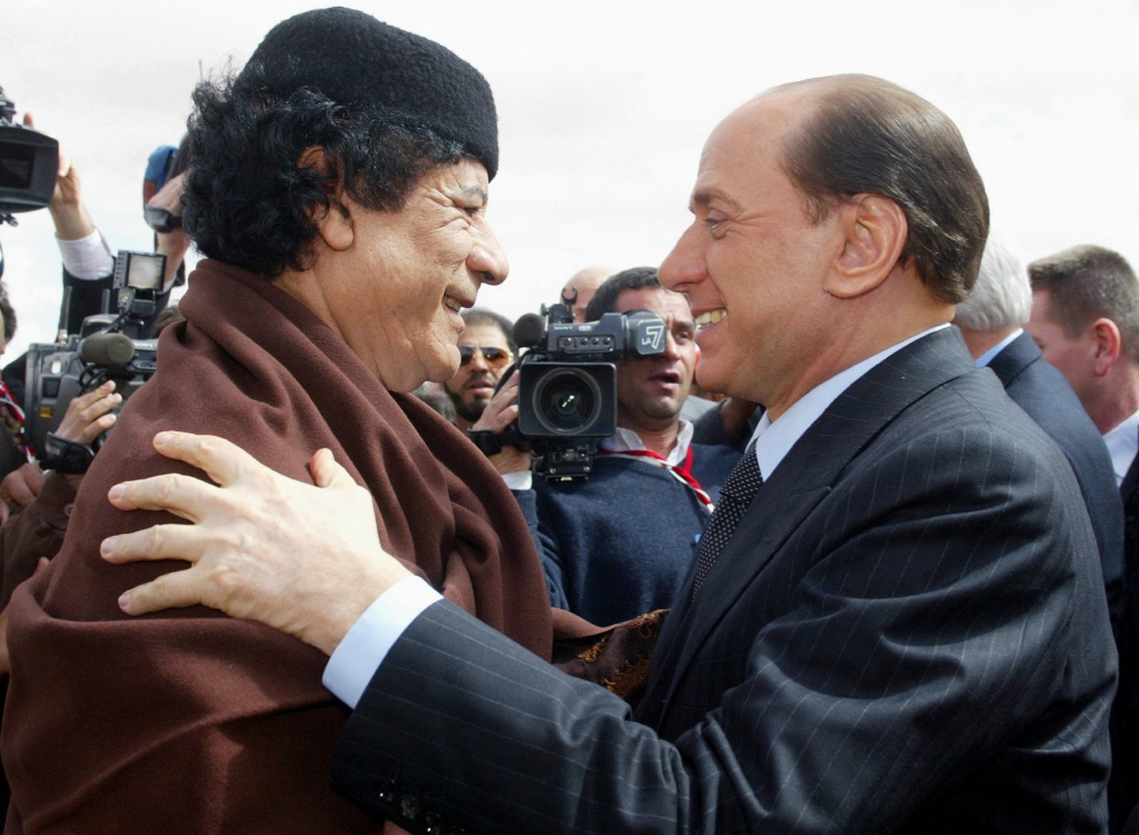 Libyan leader Moamer Kadhafi greets Italian Prime Minister Silvio Berlusconi during a meeting in Sirte, on Feb. 10, 2004. 
