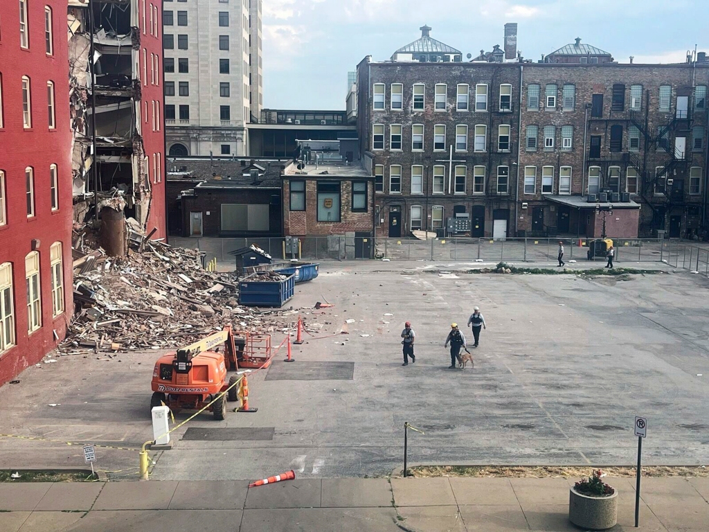 Three search and rescue workers and a dog approach the site of a building collapse in Davenport, Iowa.