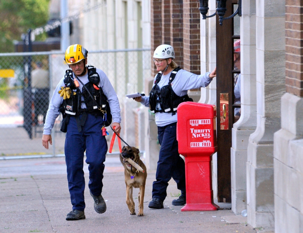 Search and rescue K-9 handlers exit the front entrance of The Davenport apartments.