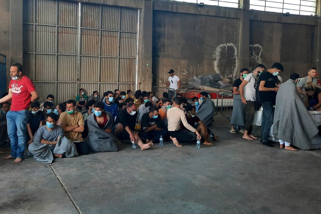 Survivors of the shipwreck sit at a warehouse at the port in Kalamata town on June 14, 2023.