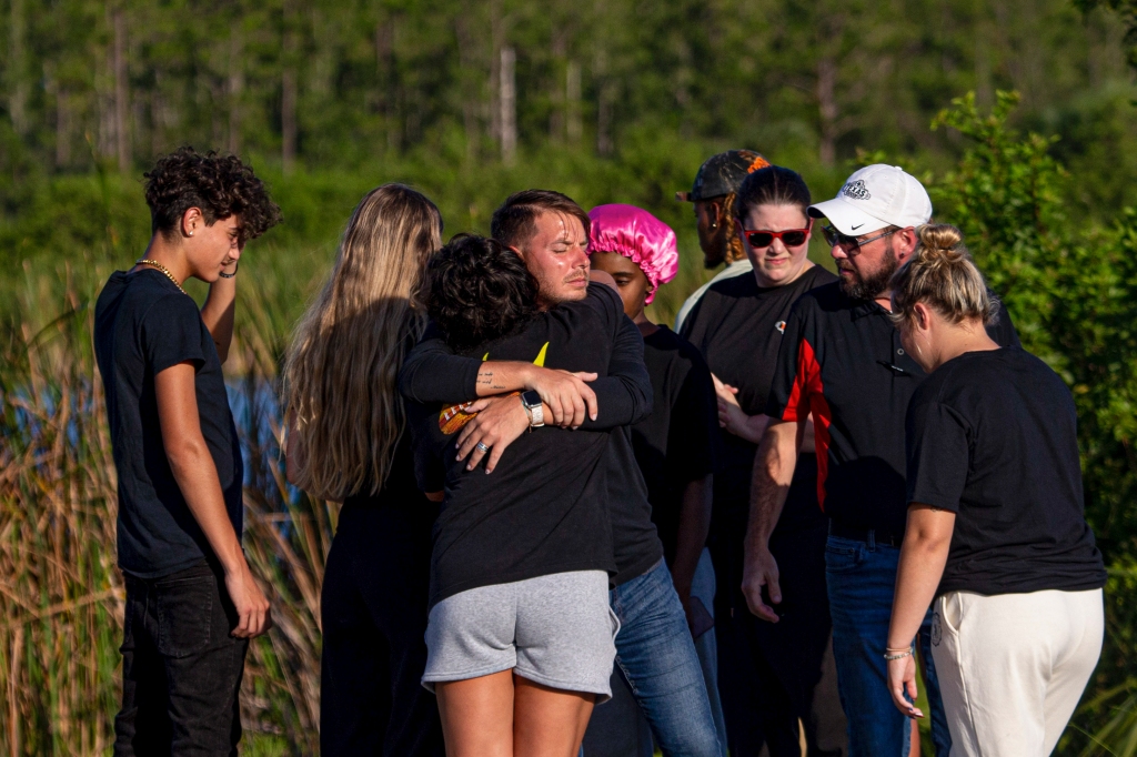 People embrace at the scene where five teenagers were found dead in a submerged car in a retention pond in Fort Myers, Fla., on June 26, 2023.