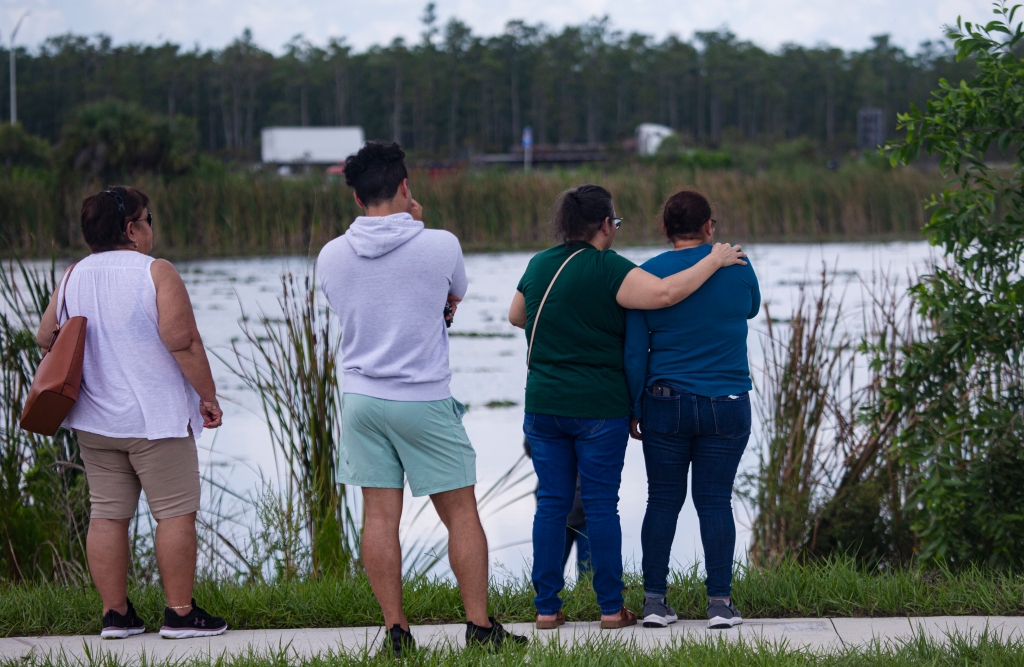 People gather at the scene where five teenagers were found dead in a submerged vehicle in a retention pond in Fort Myers, Fla., on June 26, 2023.