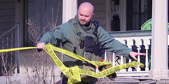 Officer unrolls police tape