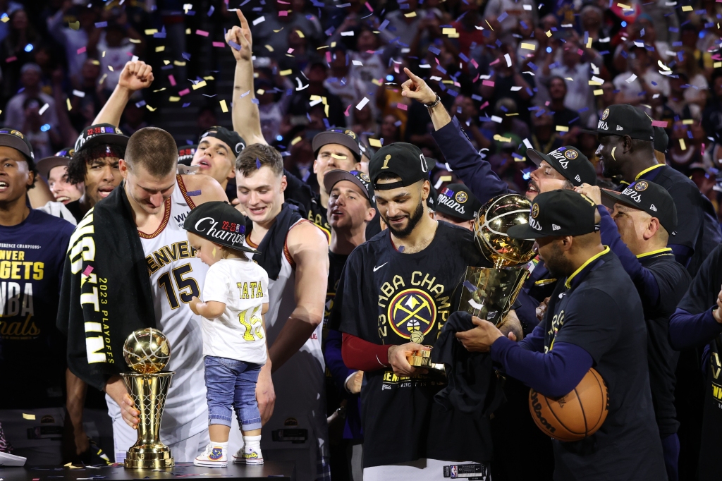Nikola Jokic is presented with the Bill Russell Finals MVP Trophy while Jamal Murray holds the Larry O'Brien Championship Trophy after Game Five of the 2023 NBA Finals on June 12, 2023 at Ball Arena in Denver, CO. 
