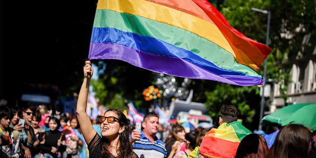 A woman at Pride event holds pride flag up