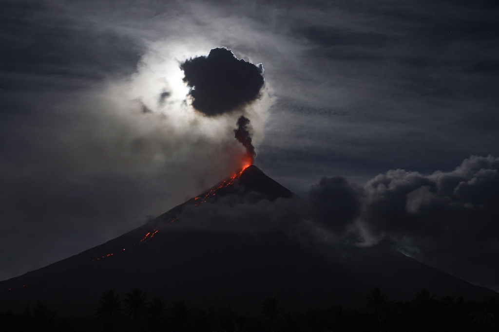 The 'super blue blood moon' obscured by clouds illuminates Mayon volcano as it spews ash near Legazpi City, Albay province, early on February 1, 2018.