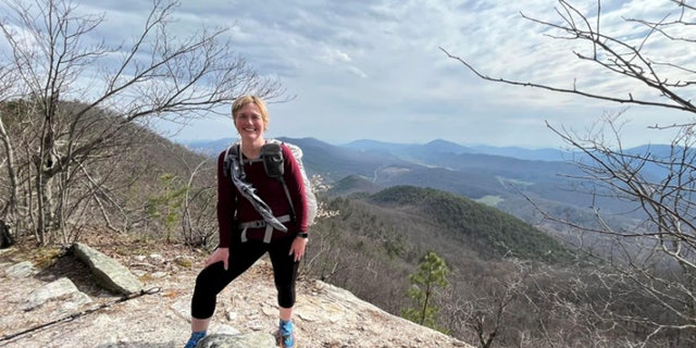 Melody Sasser poses at the top of mounting in hiking gear.